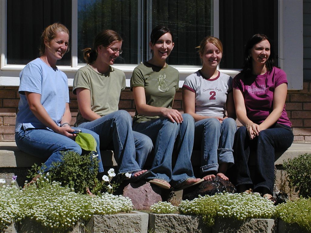 four people sitting on a stone bench in front of a building