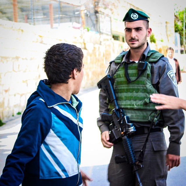 a man talking to another man with a rifle