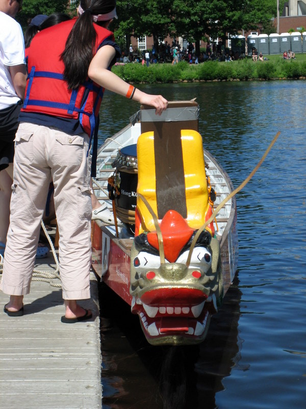 a person wearing an orange life jacket and a life jacket stands next to a boat