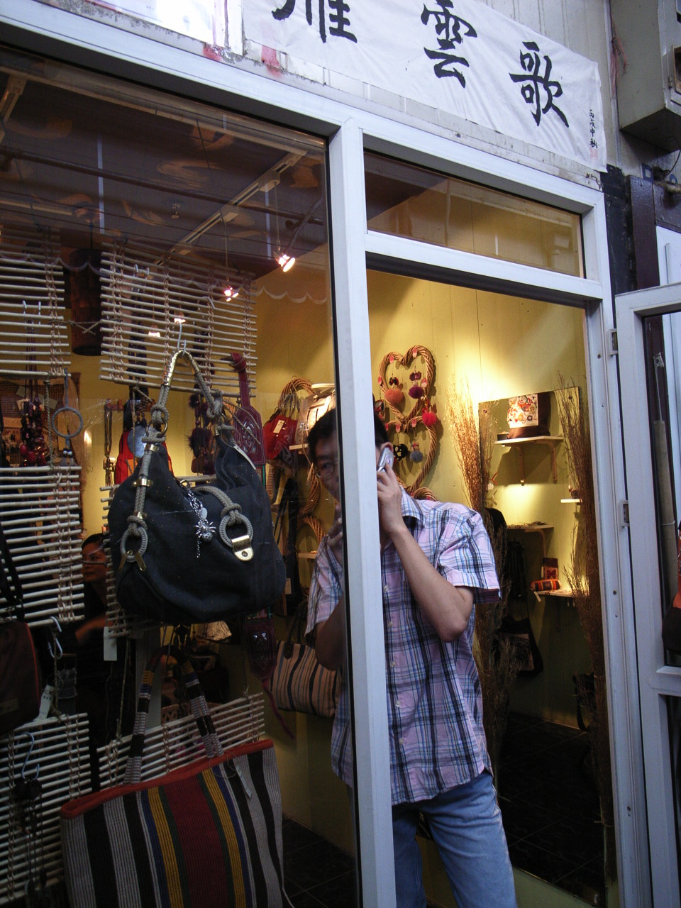 a woman holding a cell phone while looking in a store window