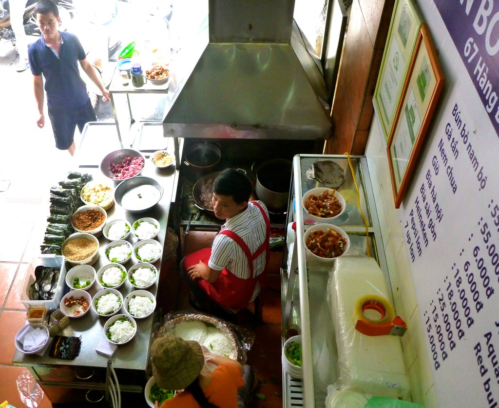 two men working in an oriental food joint with many plates of food