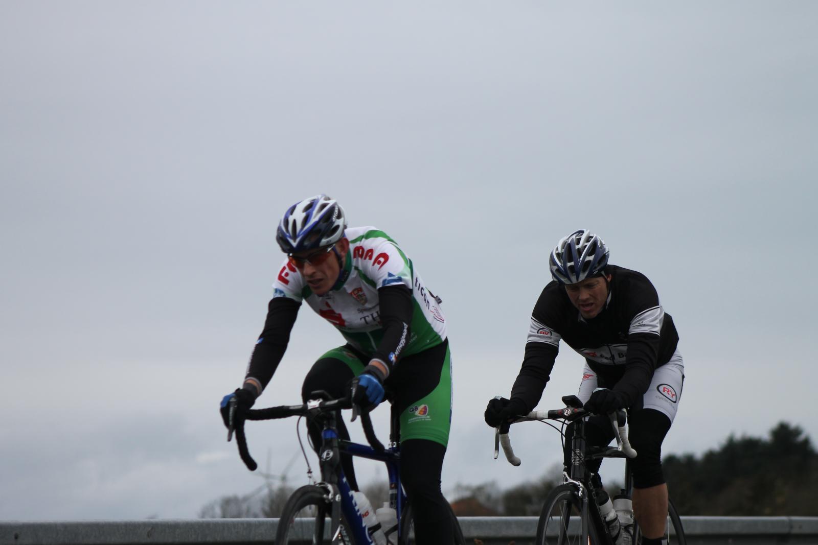 two bicyclists riding on a highway during the day