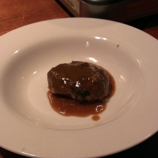 a meatball sitting on top of a white plate covered in sauce