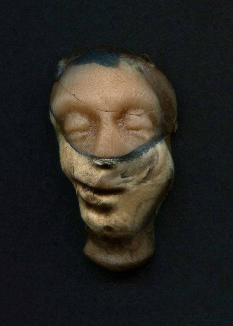 a clay face with its eyes closed and hair pulled back