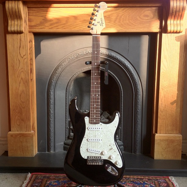 a guitar sitting in front of a fireplace
