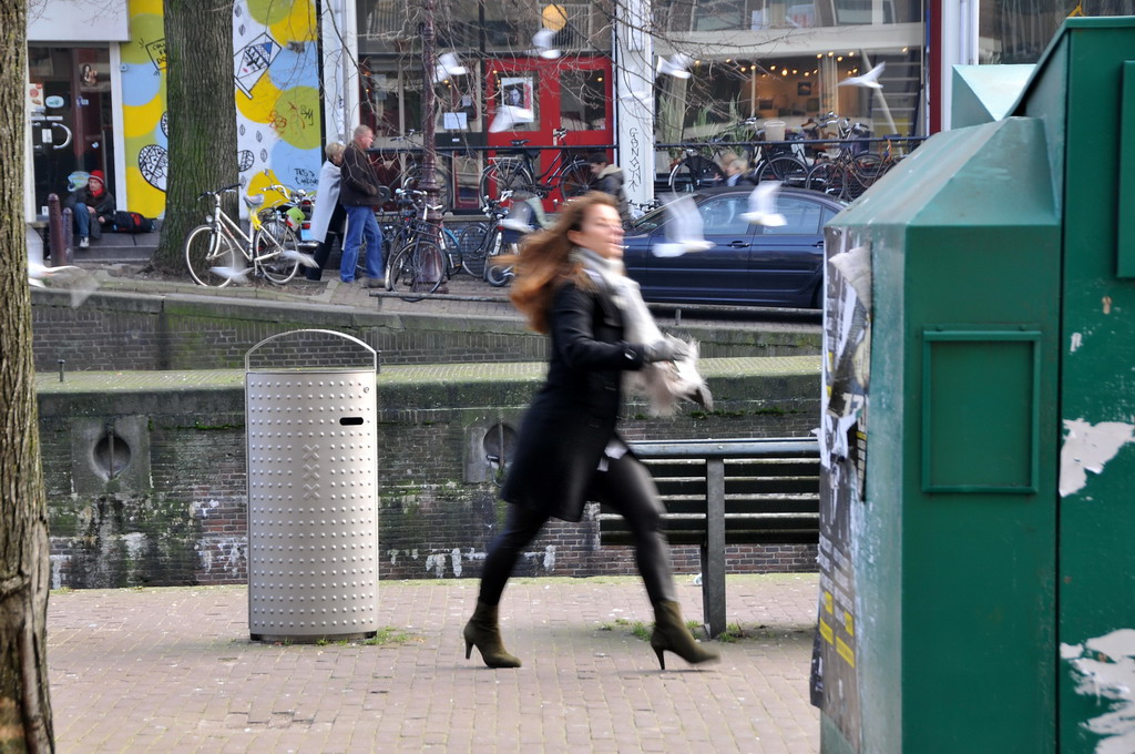 a woman walking down the street with a lot of buildings in the background