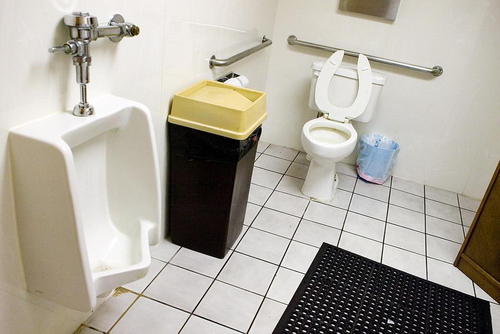 there is a sink, toilet and trash can in this small bathroom