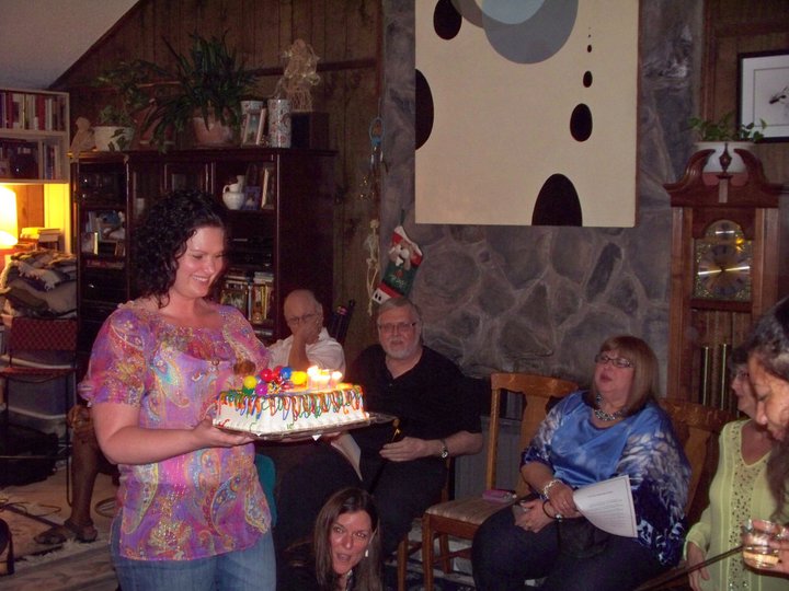 a woman holding a birthday cake surrounded by people