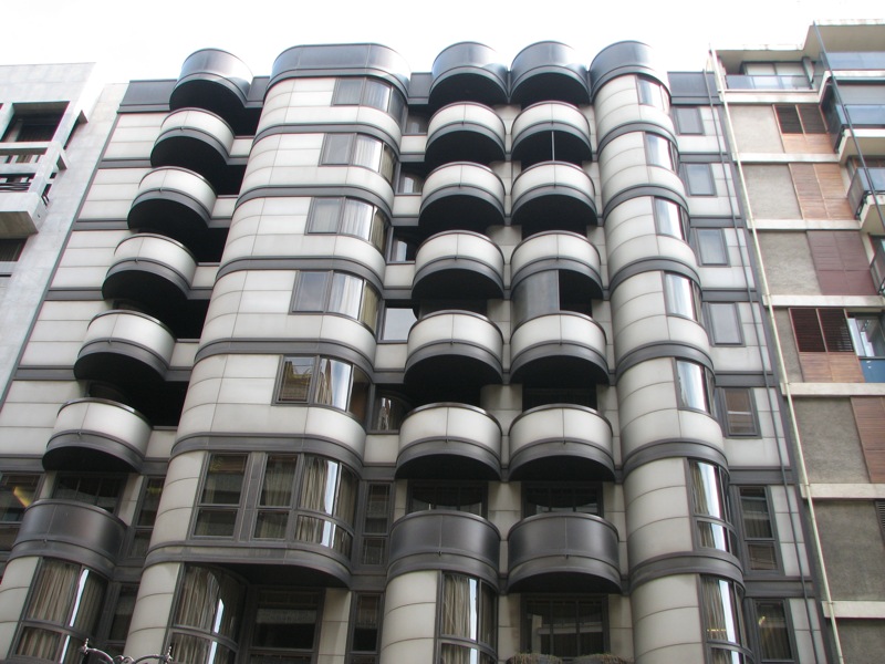 a gray building with many windows near other buildings