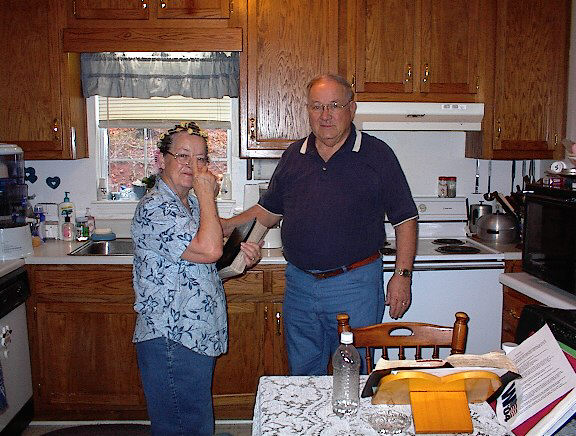 two people standing in the kitchen with one holding a bottle