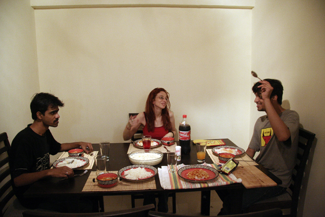 two men and a women eating food at a table