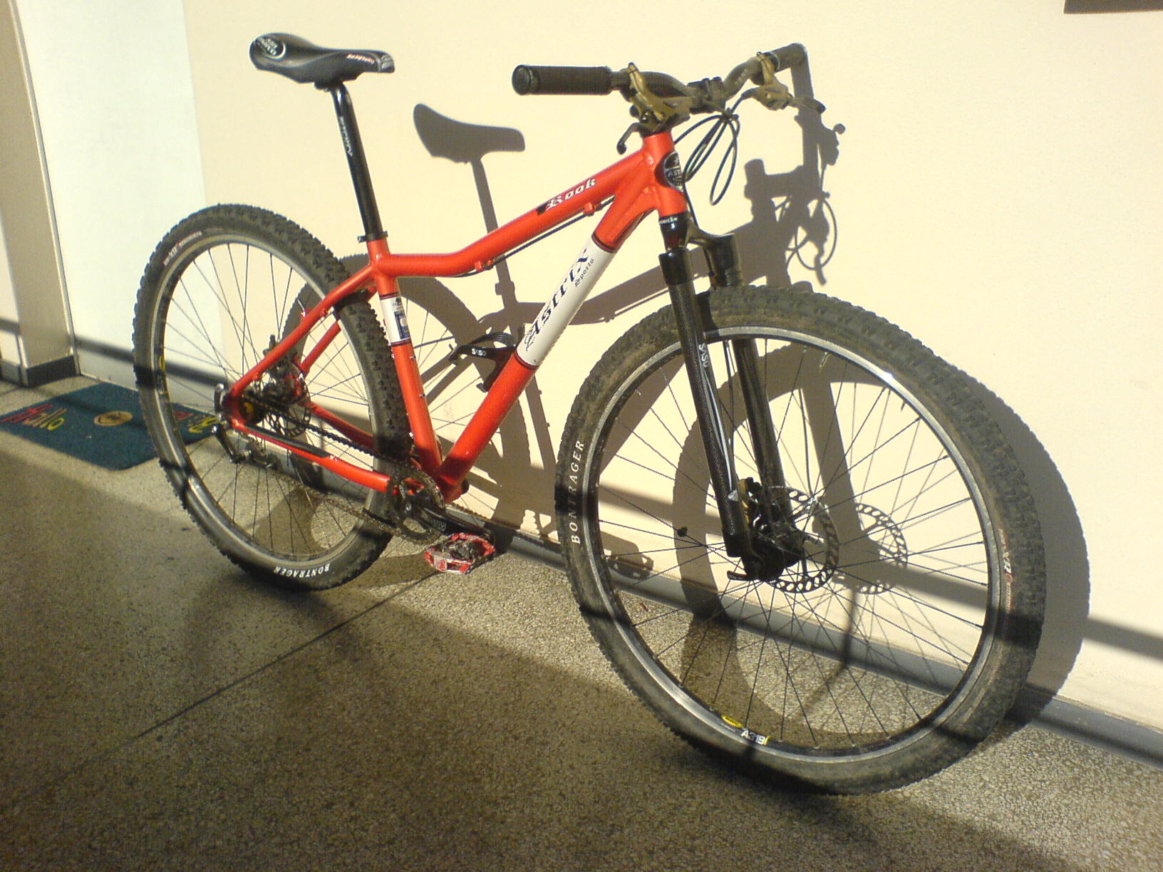 a red and black bike on its stand against a wall