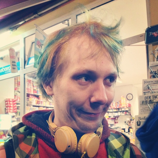 a person with multi - colored hair and headphones in front of store