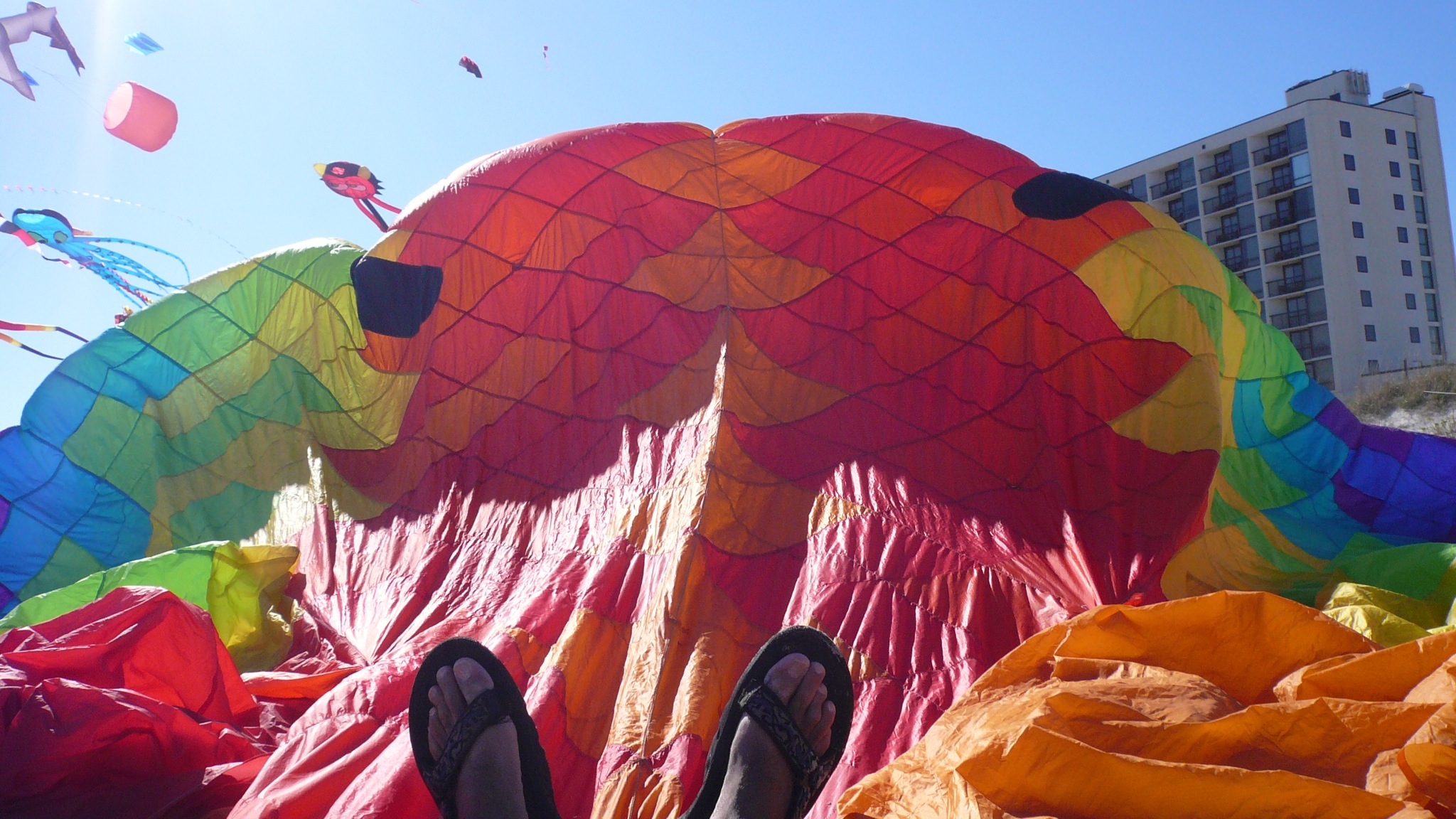 people are in a field with kites and colorful sheets