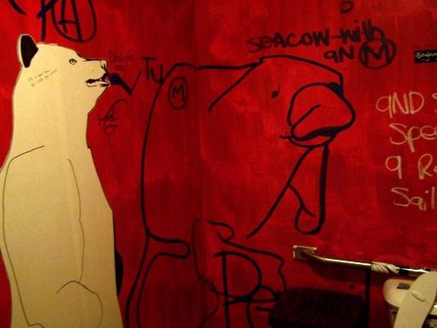 the bear is on a red wall with graffiti