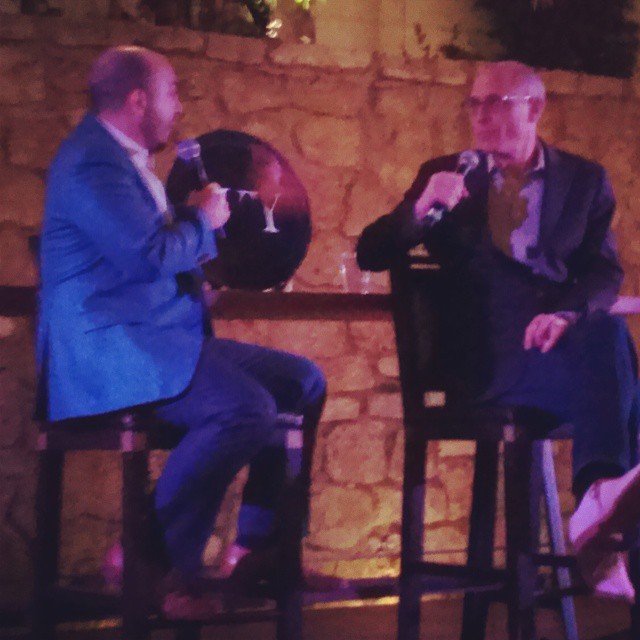 two men sit at a bar and talk to one another