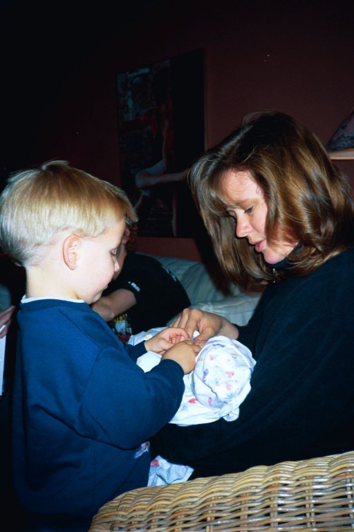 a woman is holding a baby and he has another child