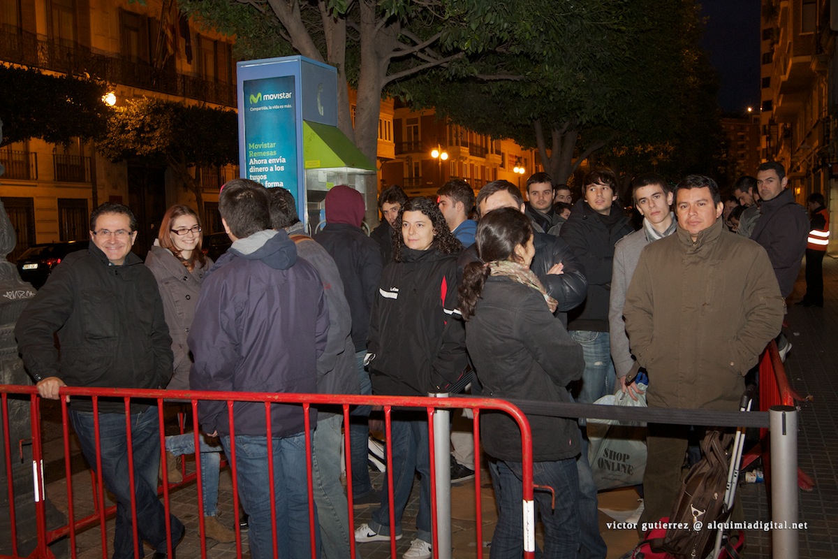 many people standing around a red railing waiting