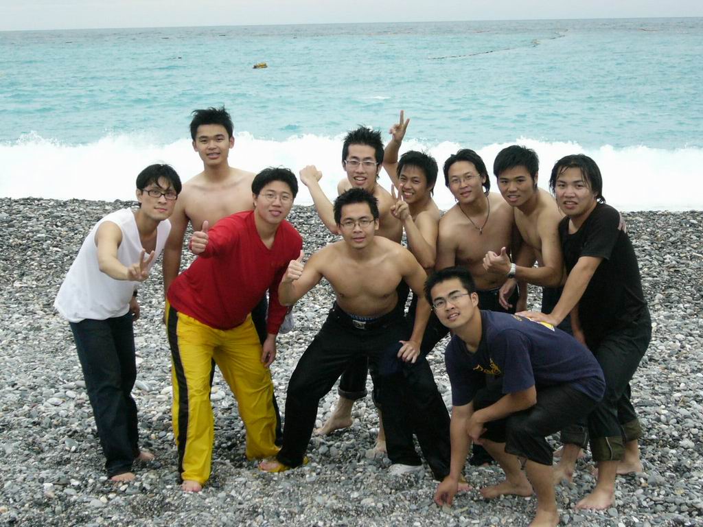 the young men are posing on the beach near the ocean