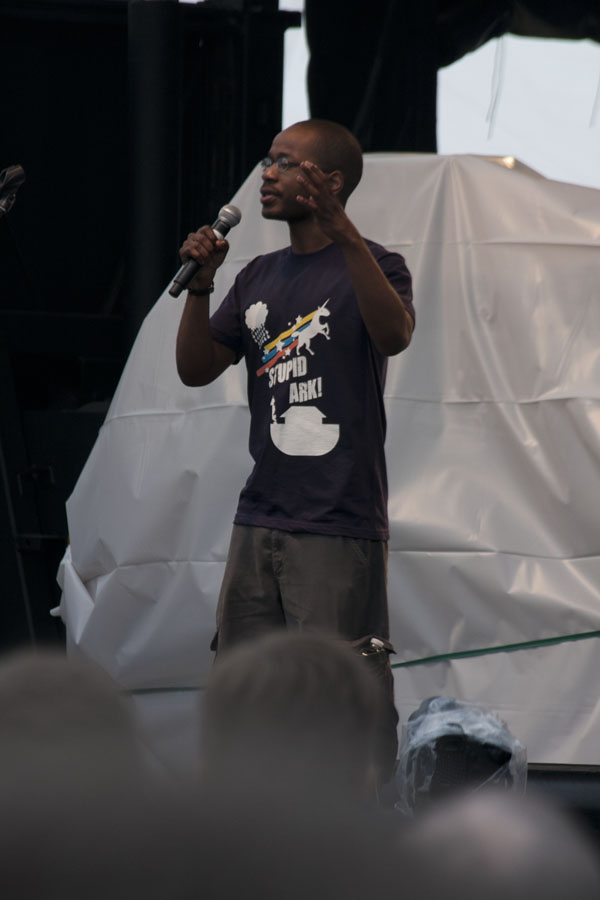 a man talking into a microphone with an audience in front of him