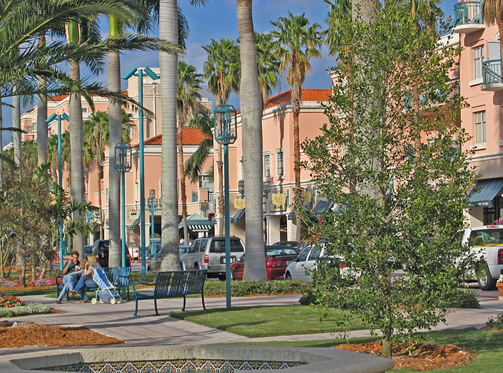 a man sitting in a chair on the sidewalk by some palm trees