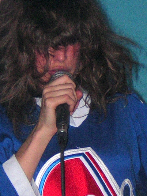 the man with long hair is singing into a microphone