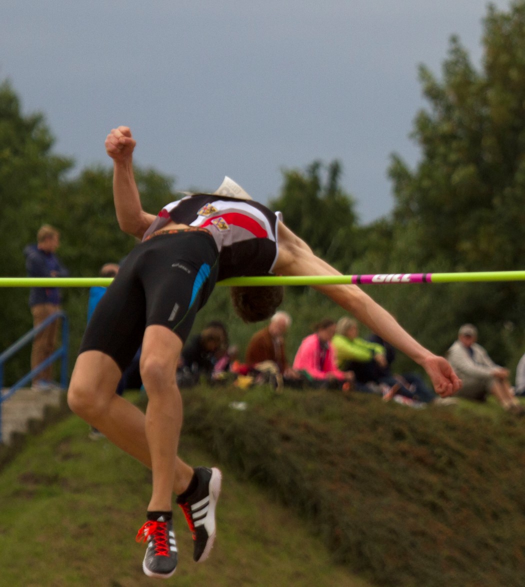 a man jumping over a bar on top of a field