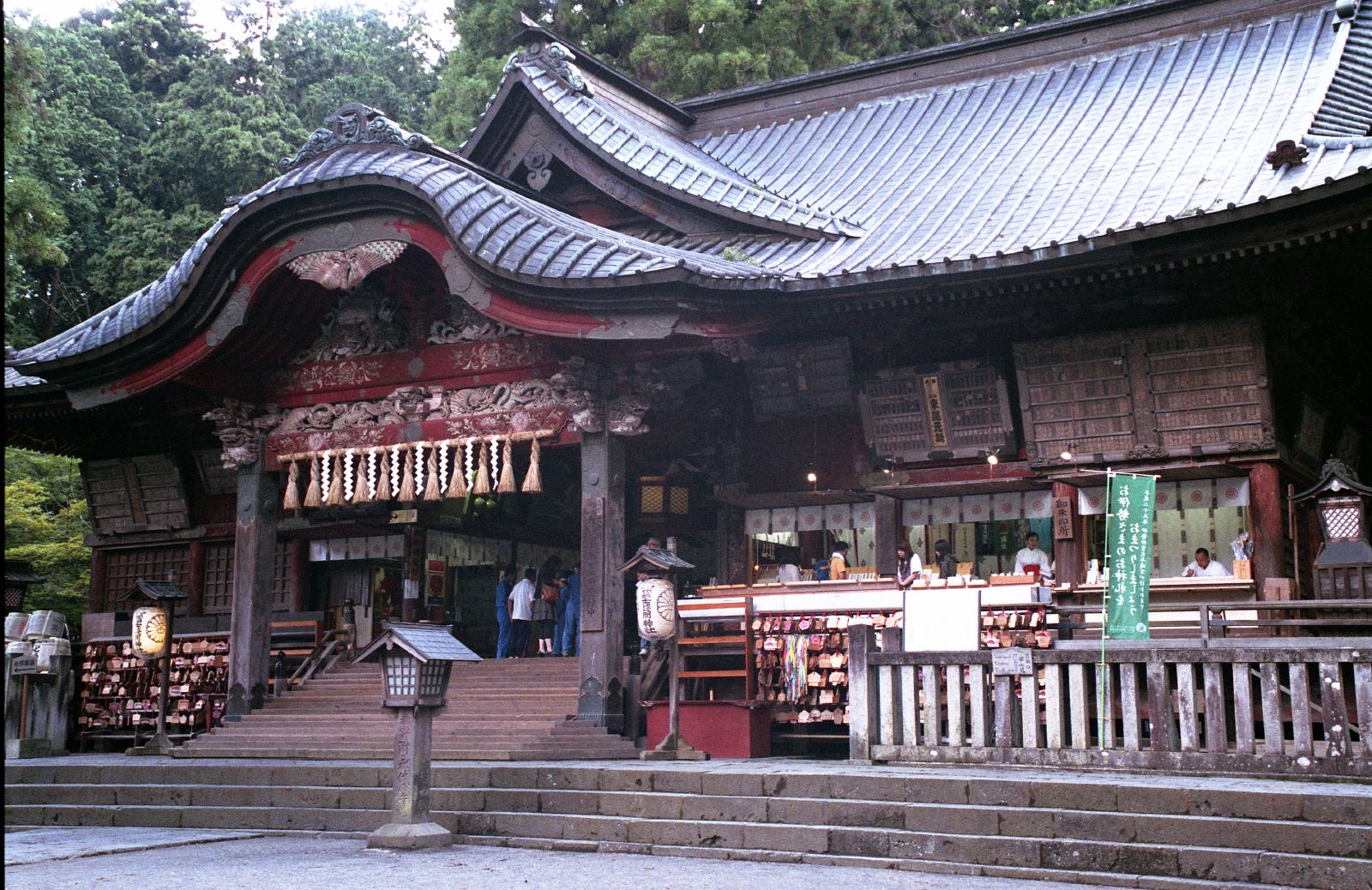 a shrine with a red roof next to some stairs