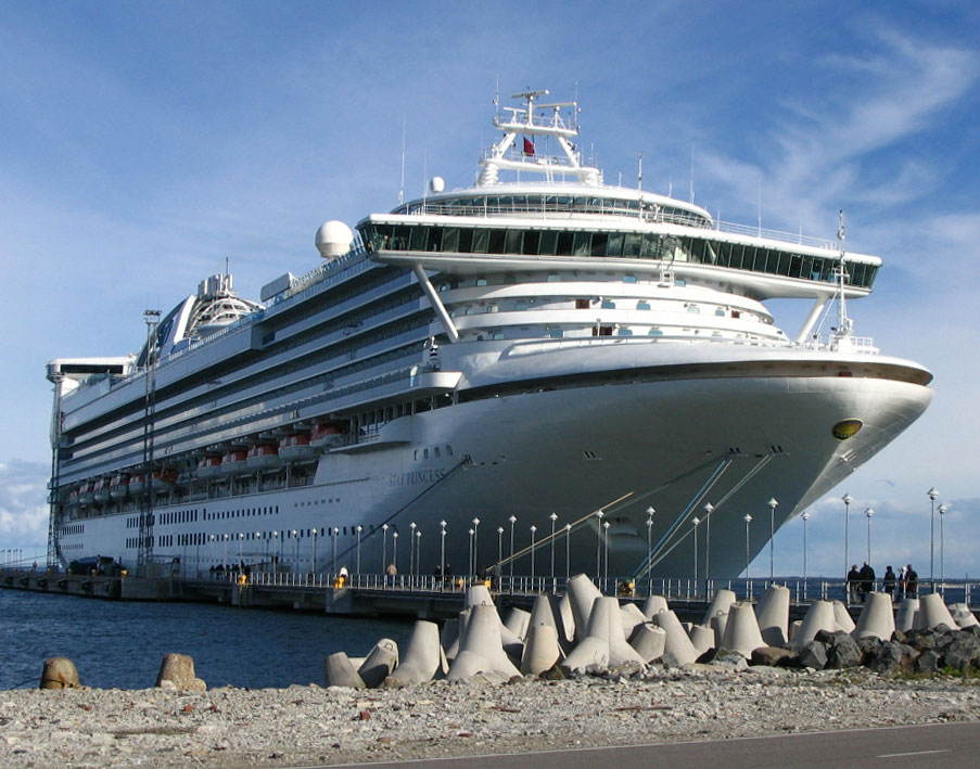 a cruise ship docked at the ocean with lots of concrete blocks
