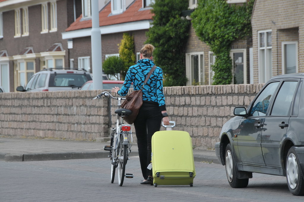 a person walking by a car with a bag next to a bicycle