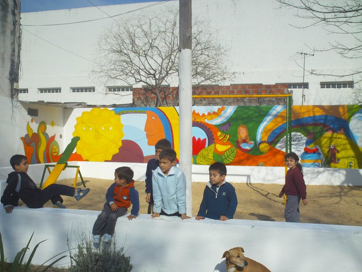 several children and a dog sitting near a mural