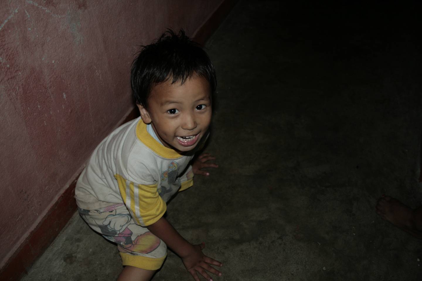 a small boy is standing near a red wall