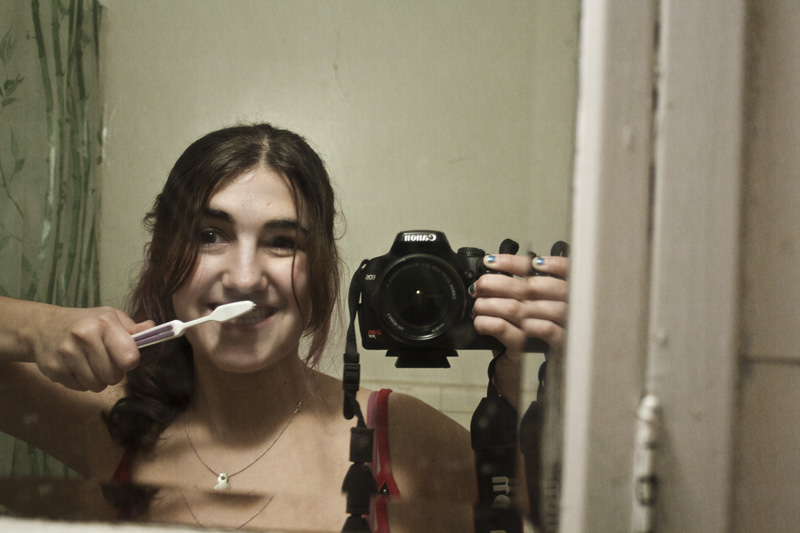 a young woman brushing her teeth in front of the mirror