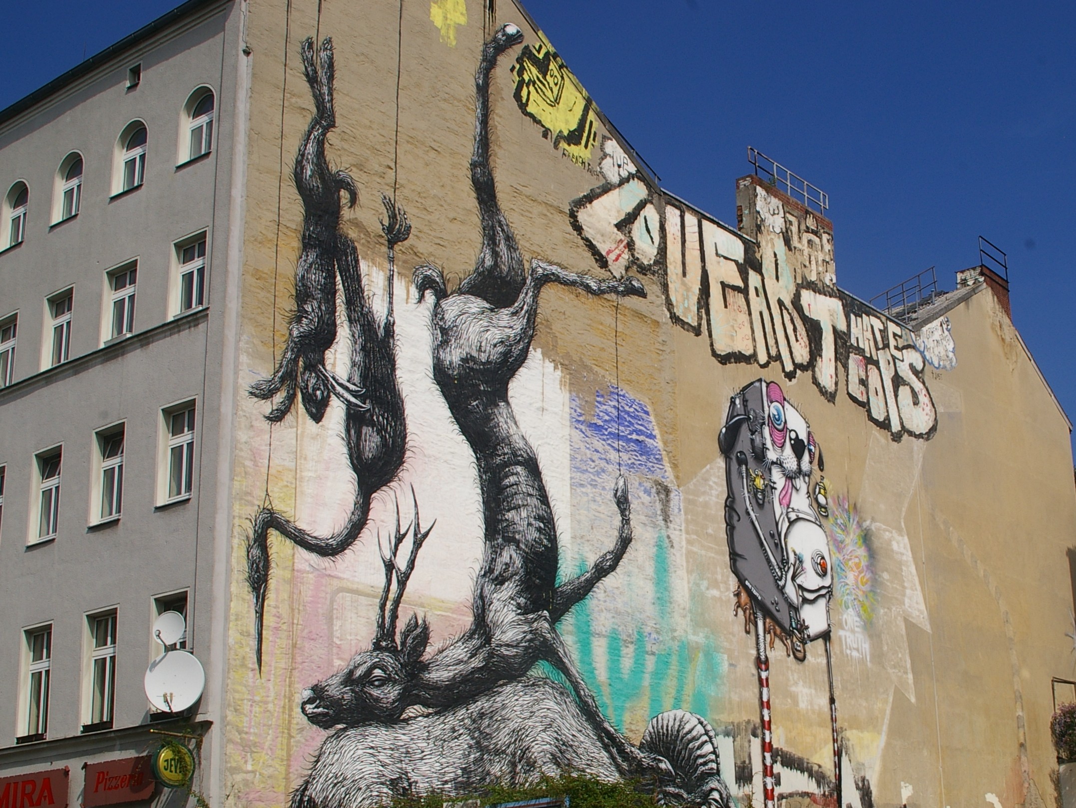 large wall painting of a stylized cat on a wall with a building in the background