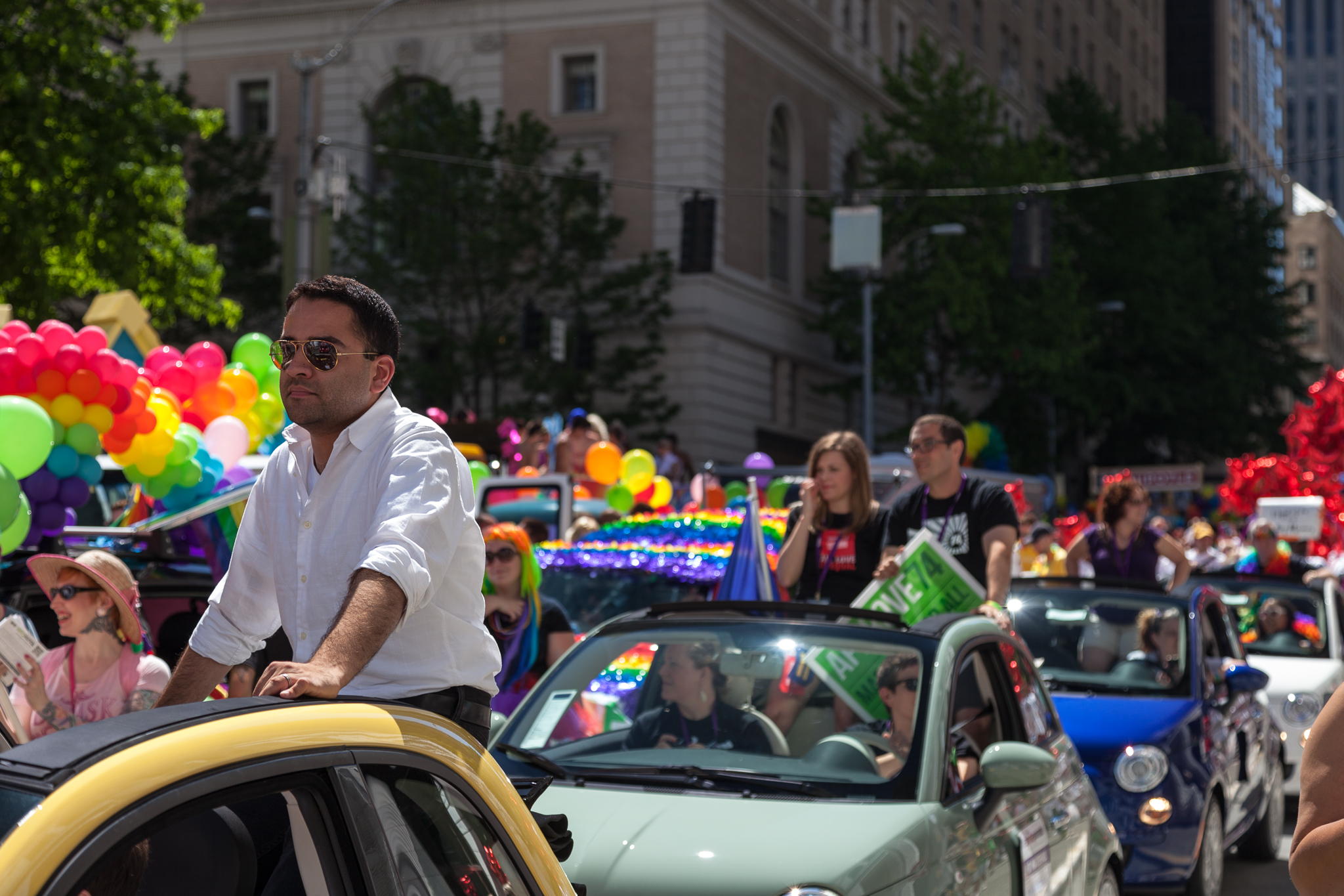 a man rides in the back of a car through a street parade