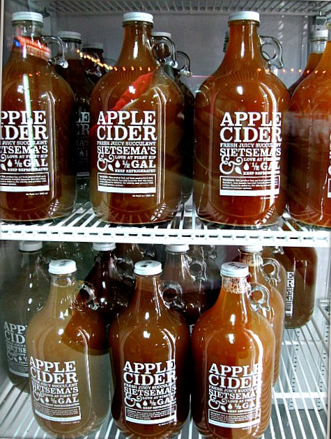 many glass bottles with apple cider on display for sale