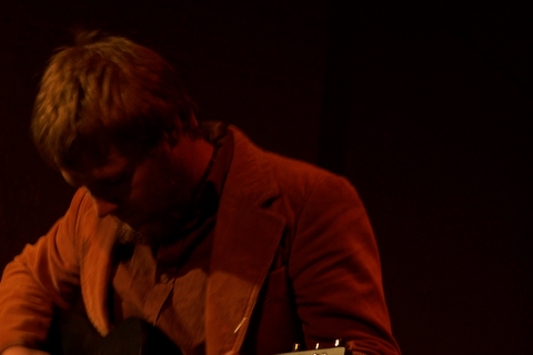 a man in a red jacket playing a guitar