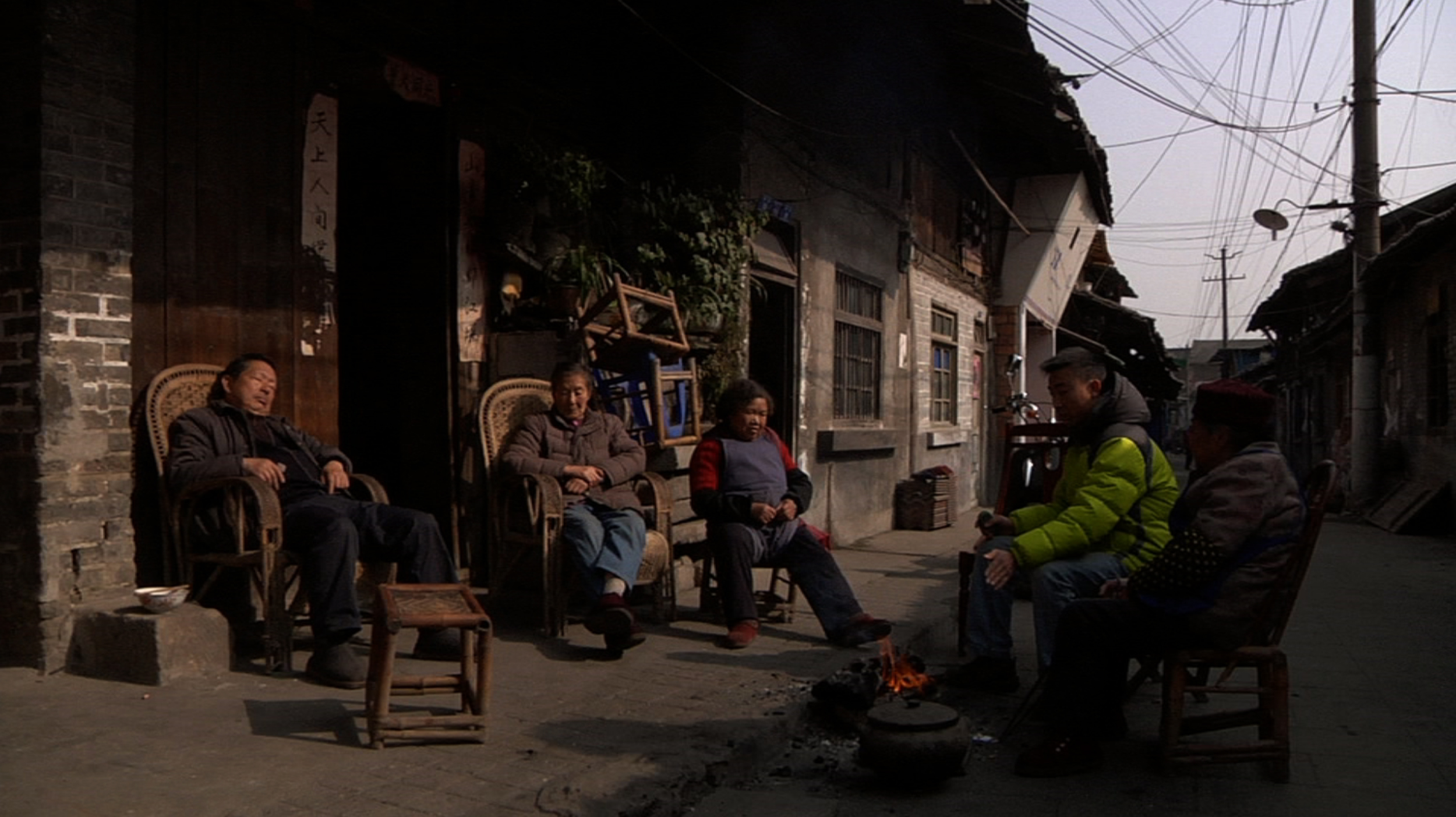 four people sit outside in rocking chairs near buildings