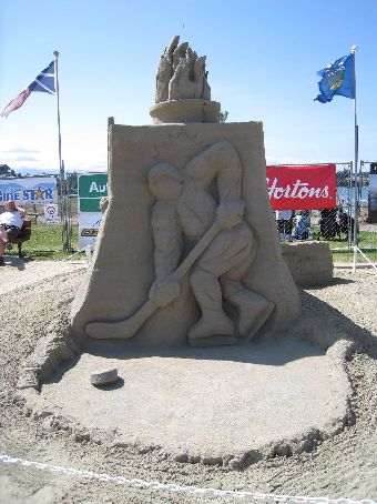 a sand sculpture of a man in a garden with two small flags