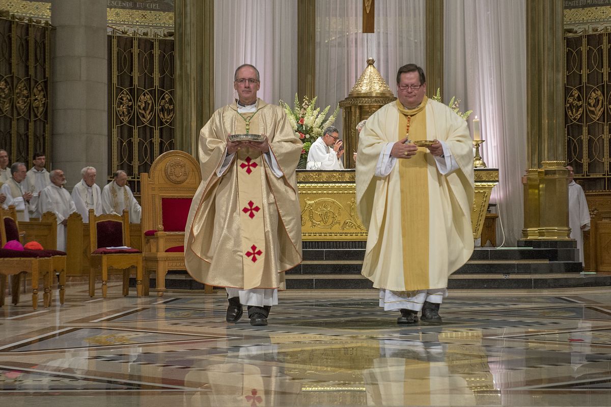 two priests standing next to each other in a church