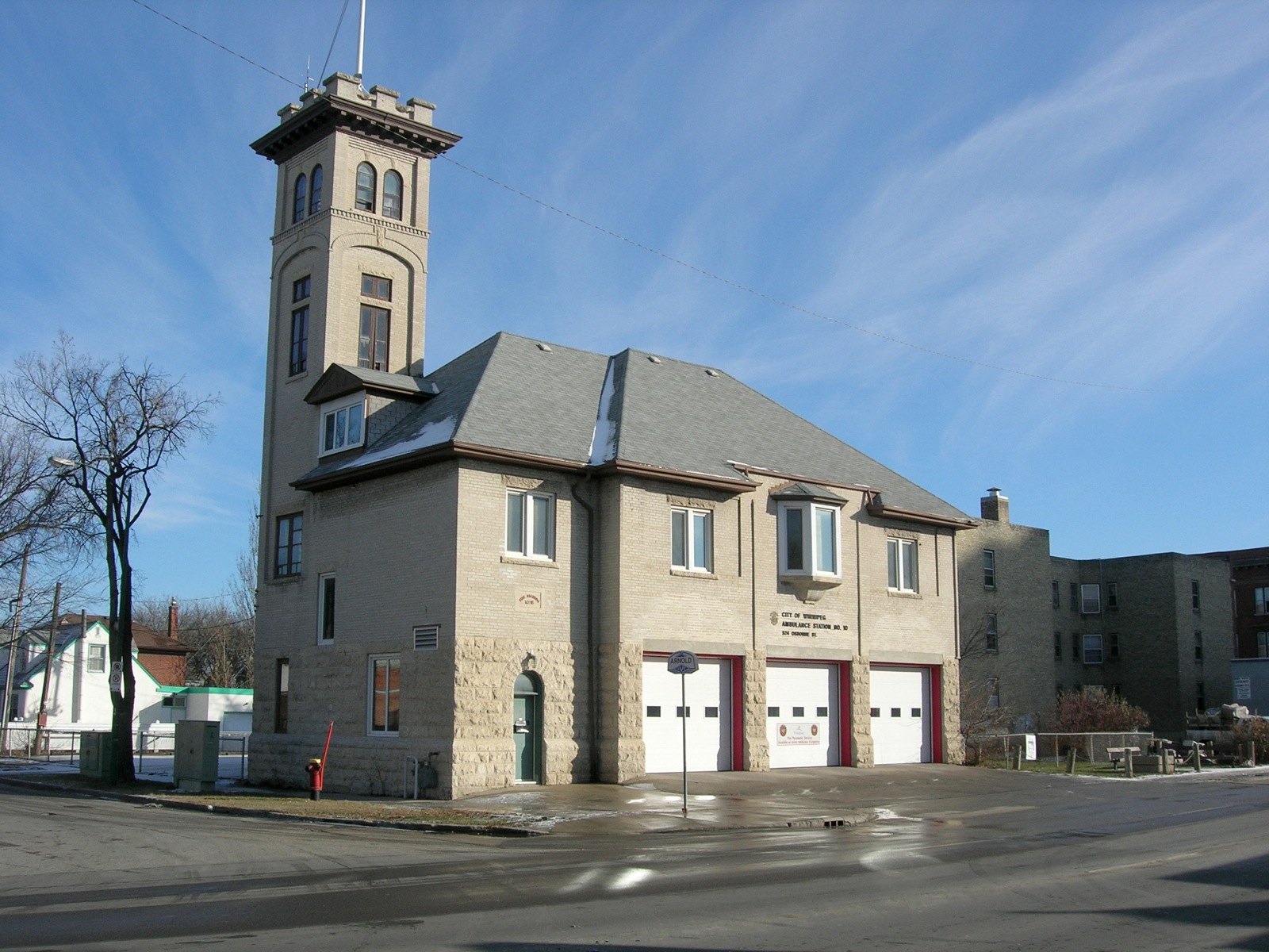 a large grey building with a clock tower near the street