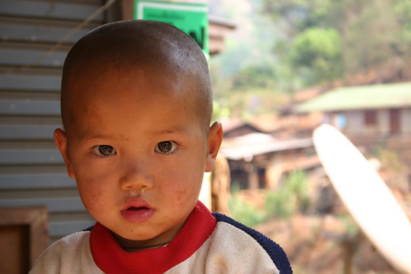 a baby standing in front of a surf board