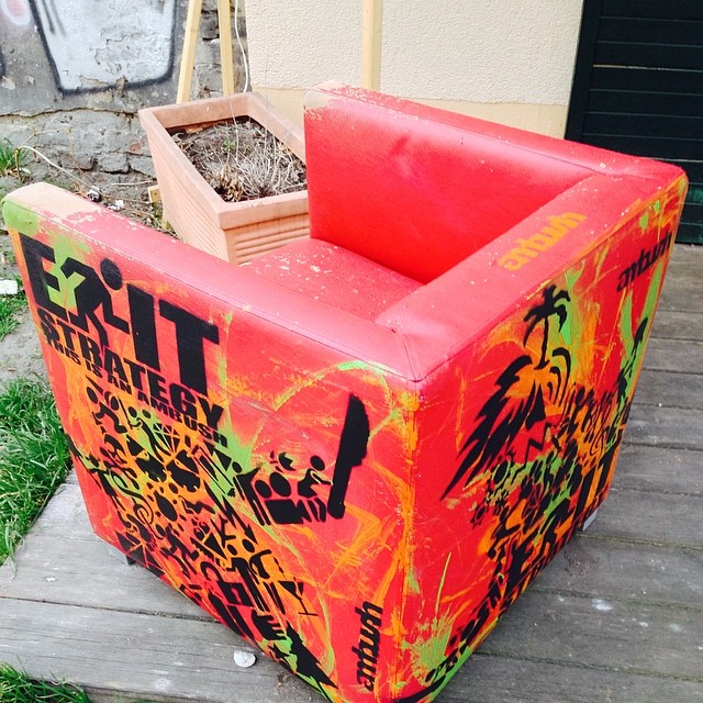 a wooden planter box with a red back, and a graffitied design