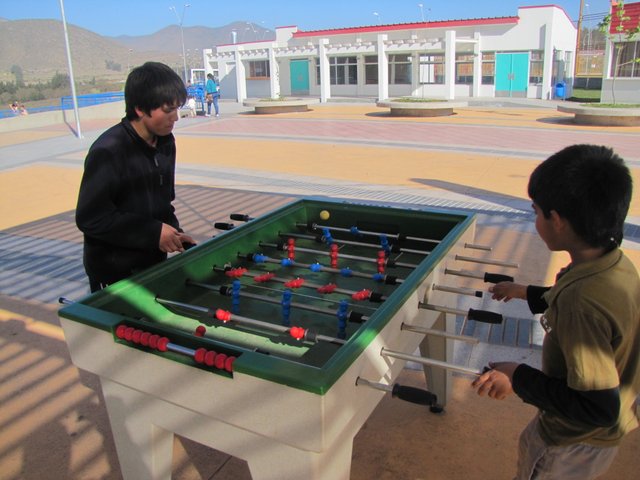 two people playing table soccer inside of a public area