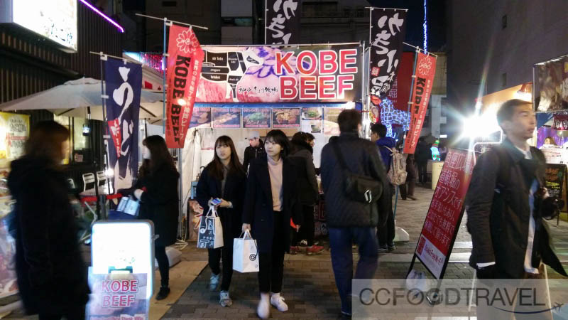 a group of people walking down a street under colorful lights