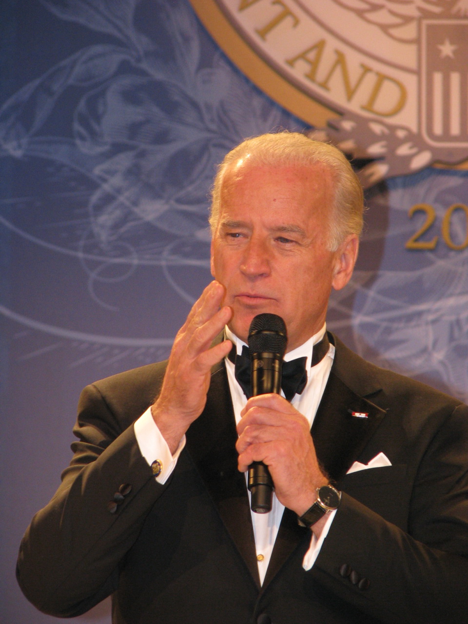 a man in a tuxedo talking into a microphone