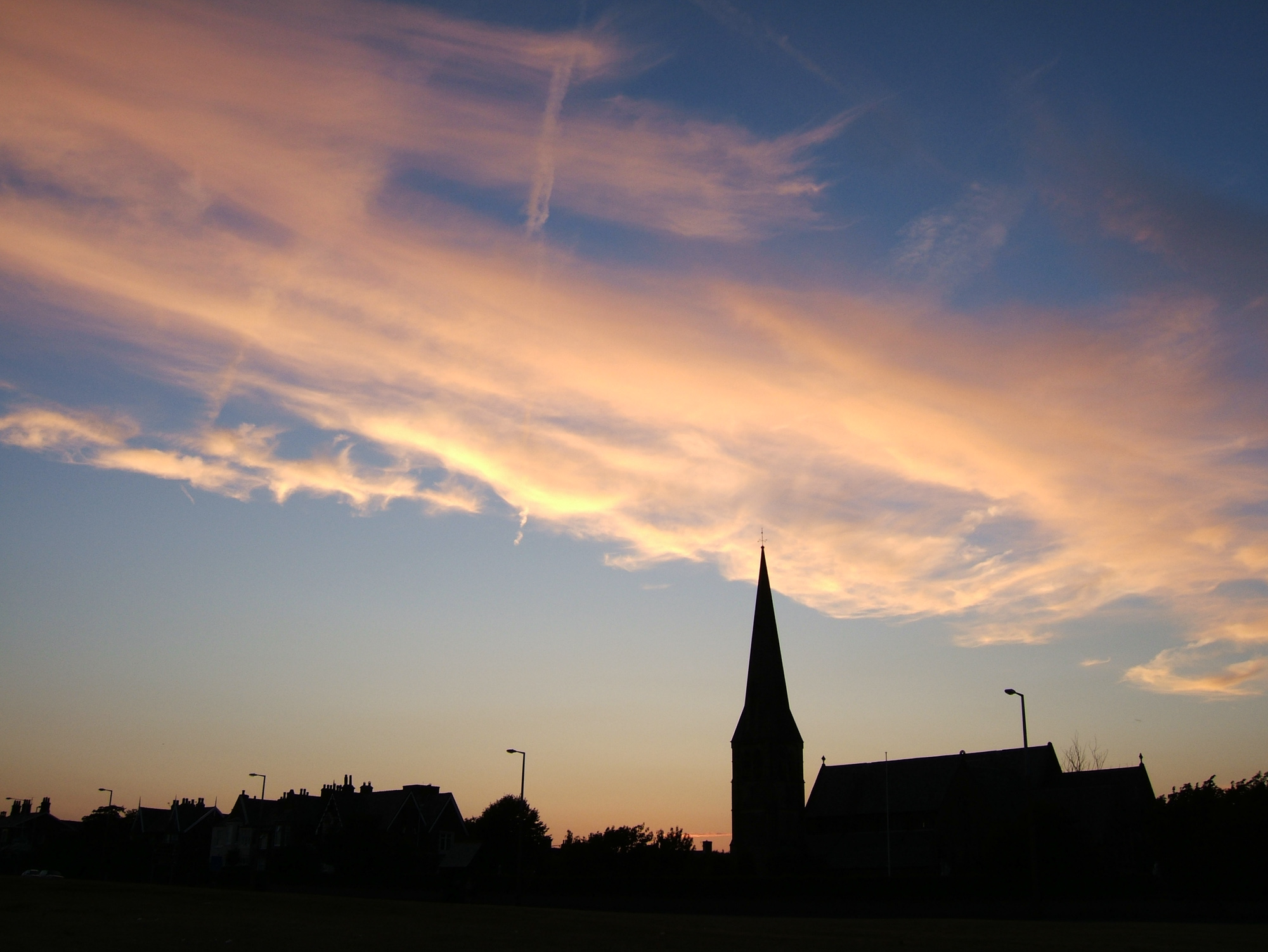 a church spire against a colorful sunset sky
