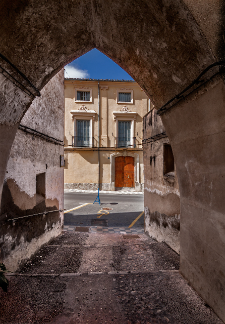 a tunnel leading to an apartment building in a stone walled area