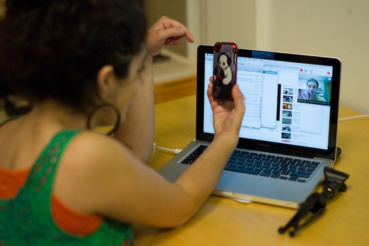 a woman holding a cell phone and touching her laptop