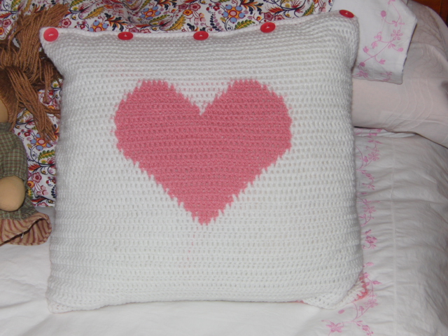 a crocheted heart is placed on a pillow